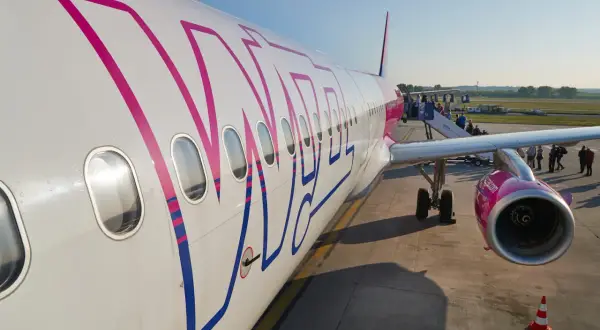 Samolot Wizz Air z widocznym logo, pasażerowie wsiadają po schodkach.