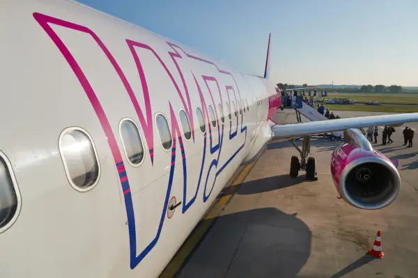 Samolot Wizz Air z widocznym logo, pasażerowie wsiadają po schodkach.